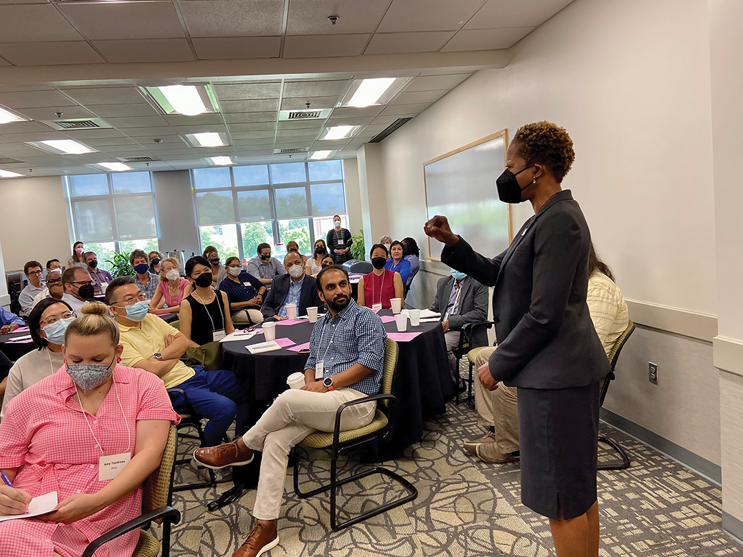 A room full of new faculty listen as President Valerie Ashby Sheares shares her praise of their work.