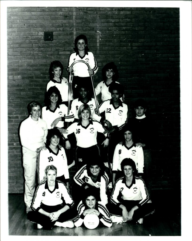 The volleyball team from 1983 poses in a black and white photo.