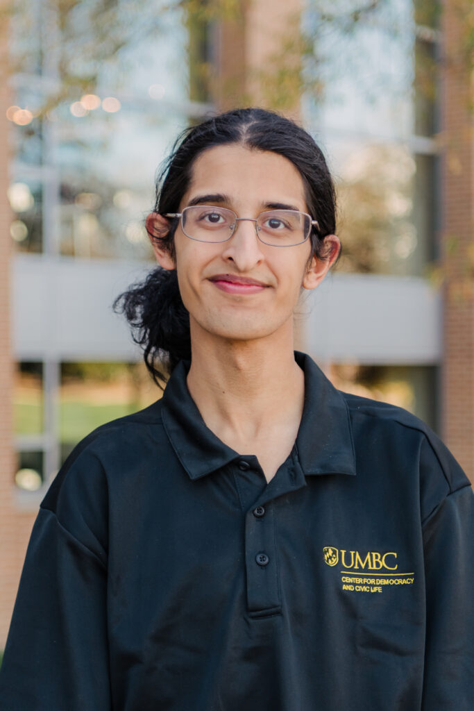 Headshot of Musa Jafri in a black polo shirt that says UMBC Center for Democracy and Civic Life. They promote elections and other democratic processes.