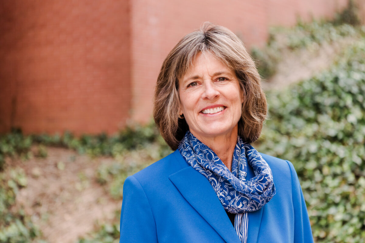 Professional portrait of woman smiling, wearing blue business suit and scarf