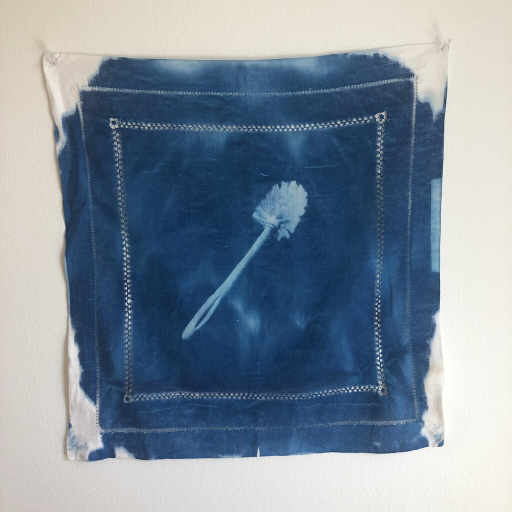 Cyanotype-coated vintage cotton napkin with an image of a toilet brush exposed using the light of the sun.