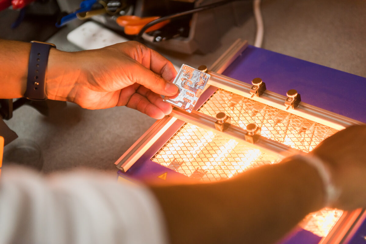 Close-up of a person's hands working on a machine with a very bright light.