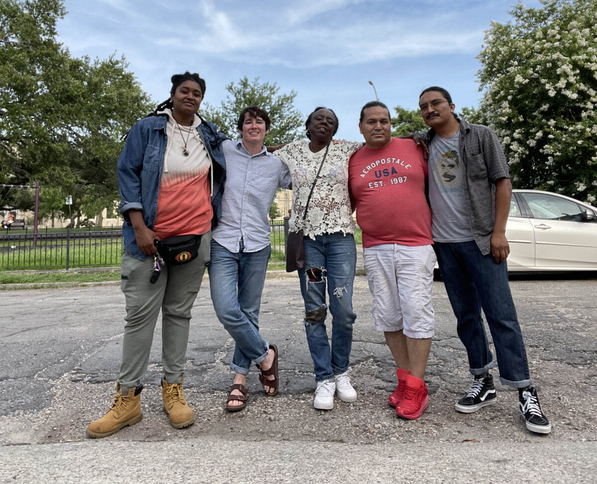 Five people stand with their arms around each others' shoulders