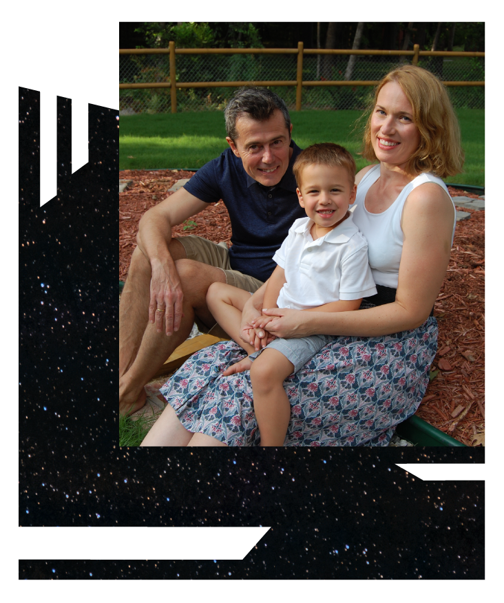 A family (father, mother, and son) poses together seated on the ground