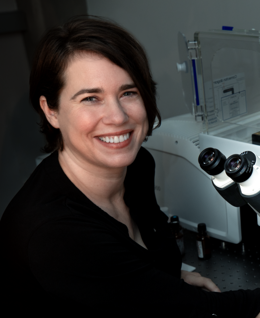 Smiling woman seated at a microscope