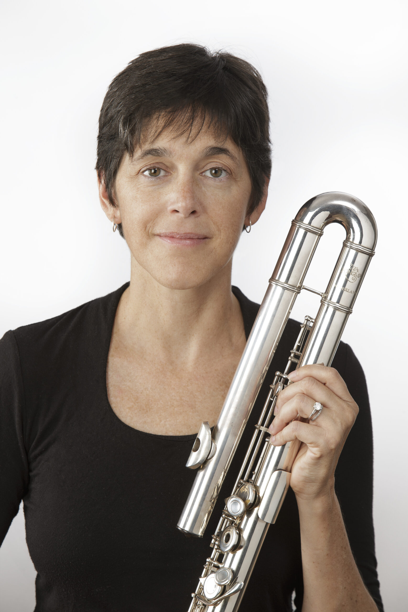 Against a white background, a white woman with short dark hair holds a bass flute