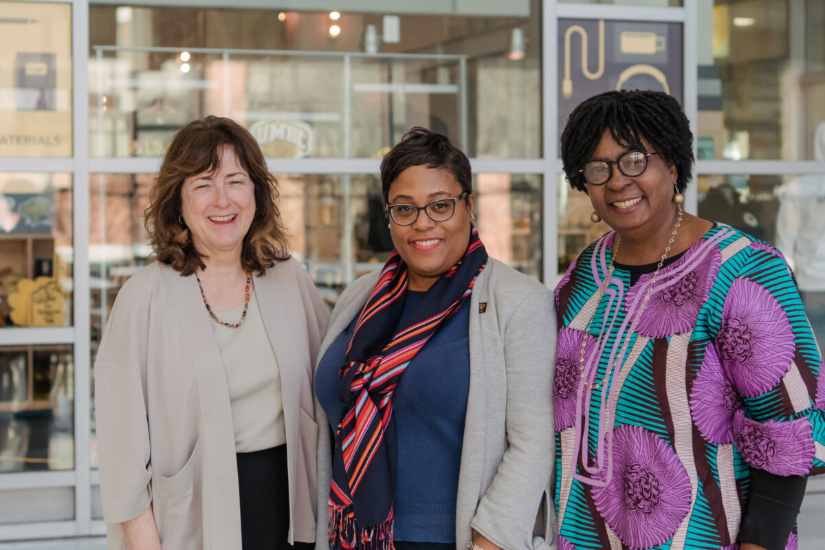 Three adults in business clothes stand next two each other as part of an Africana Studies reunion