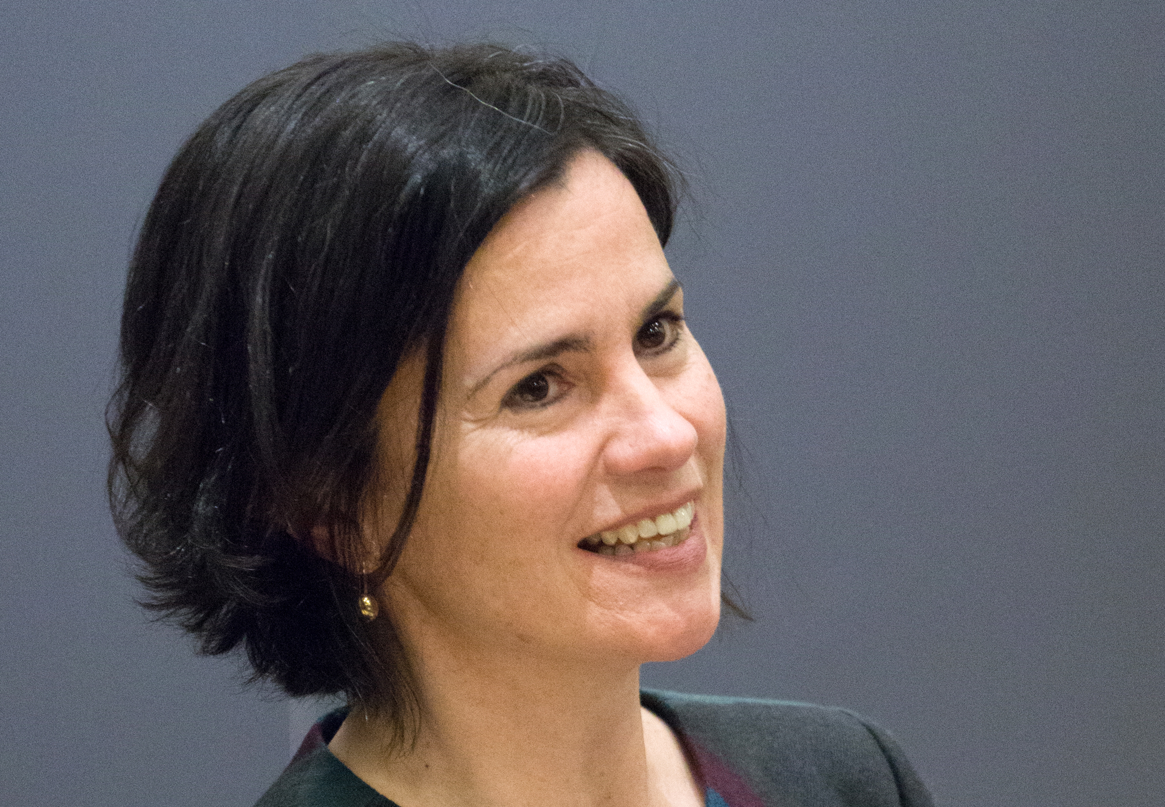 A white woman with short dark hair is smiling and looking off to the side of the camera.