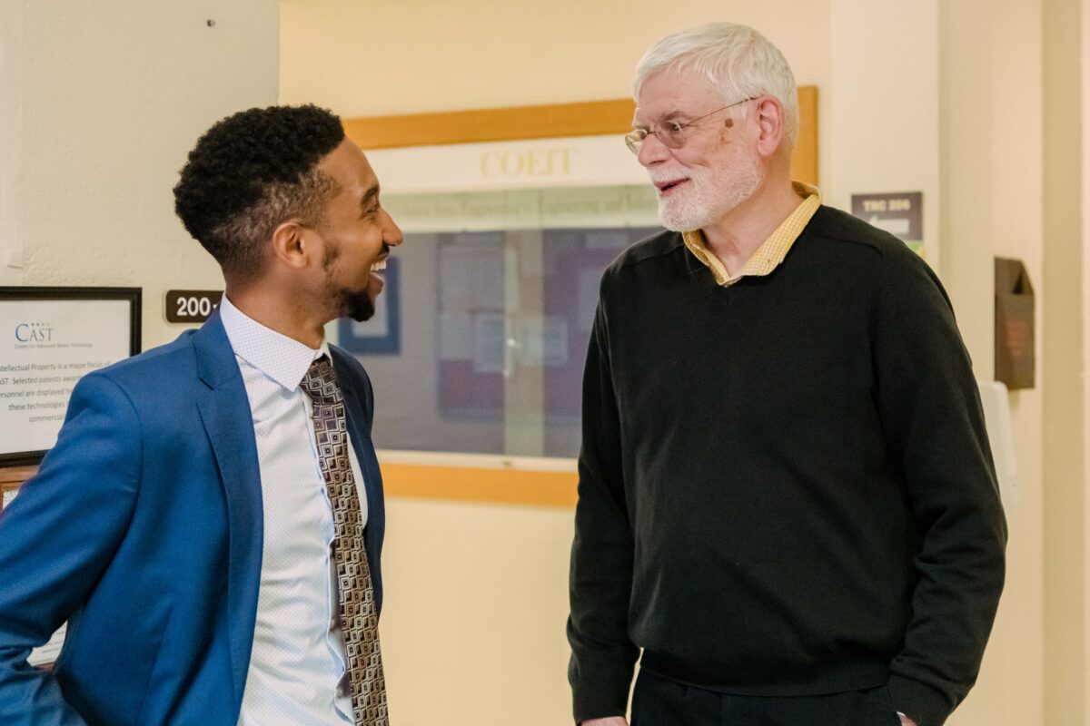 Two people chat in a hallway.