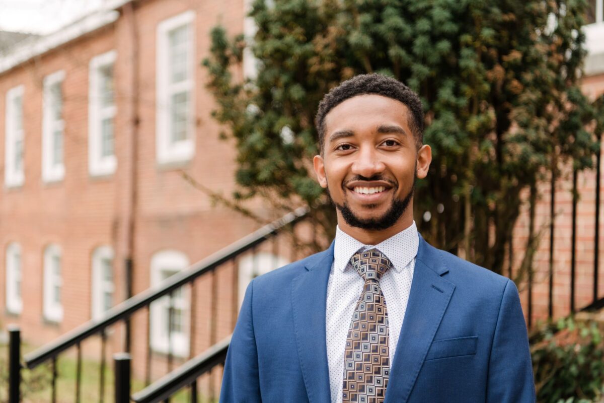 Smiling student stands in front of academic building