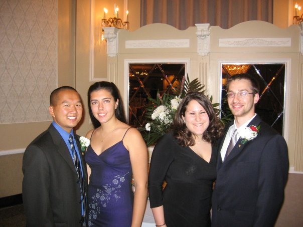 Two couples in formal wear pose together at a nice event.