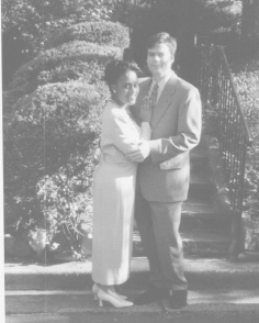 In a black and white photo, a man and woman pose together closely