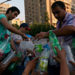 People hand over plastic bottles to be refilled with water