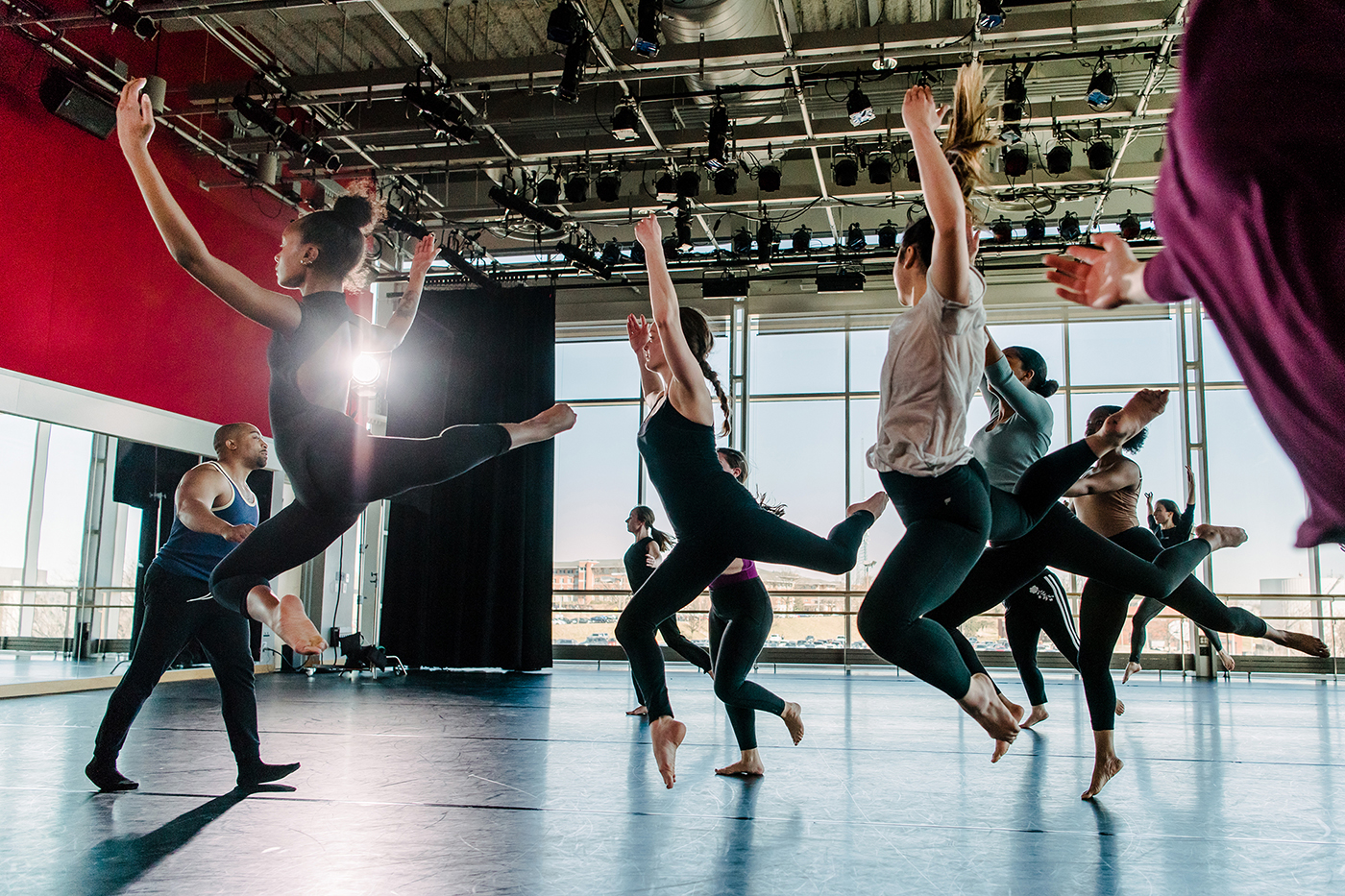 Students practice dance in a large studio.