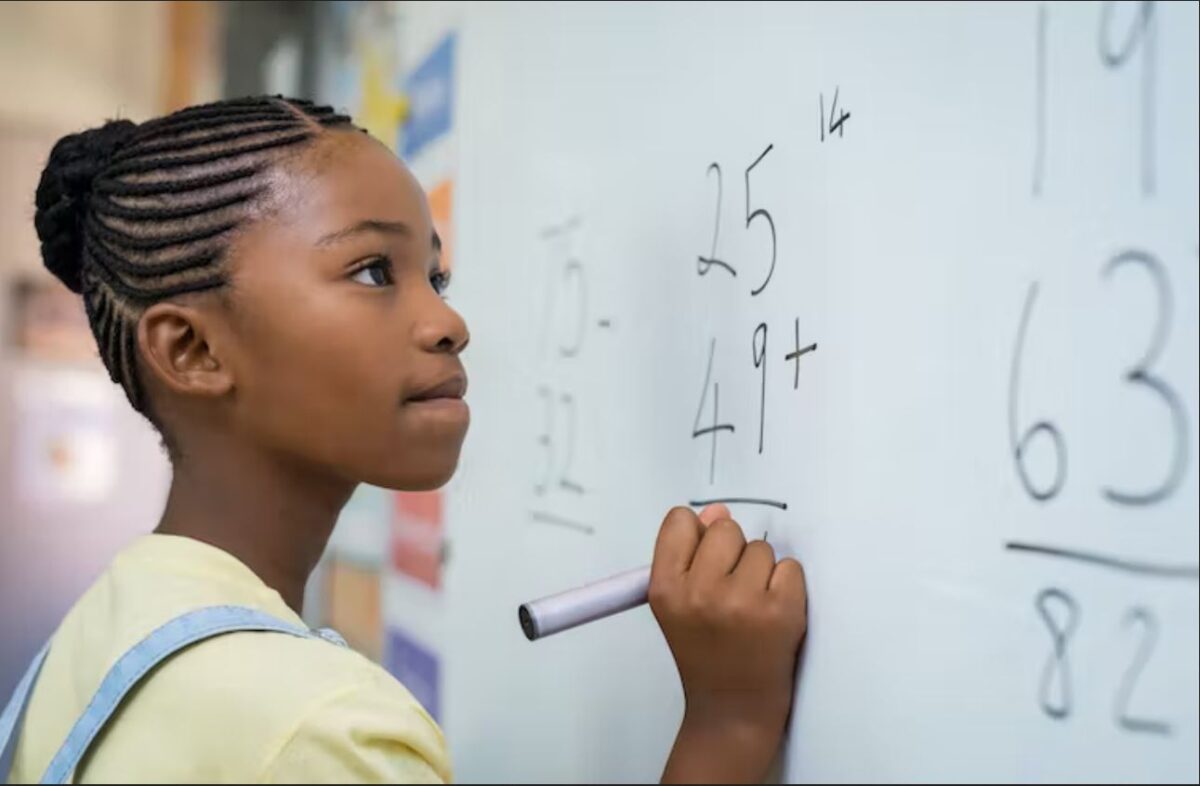 A girl writes arithmetic equations on a whiteboard