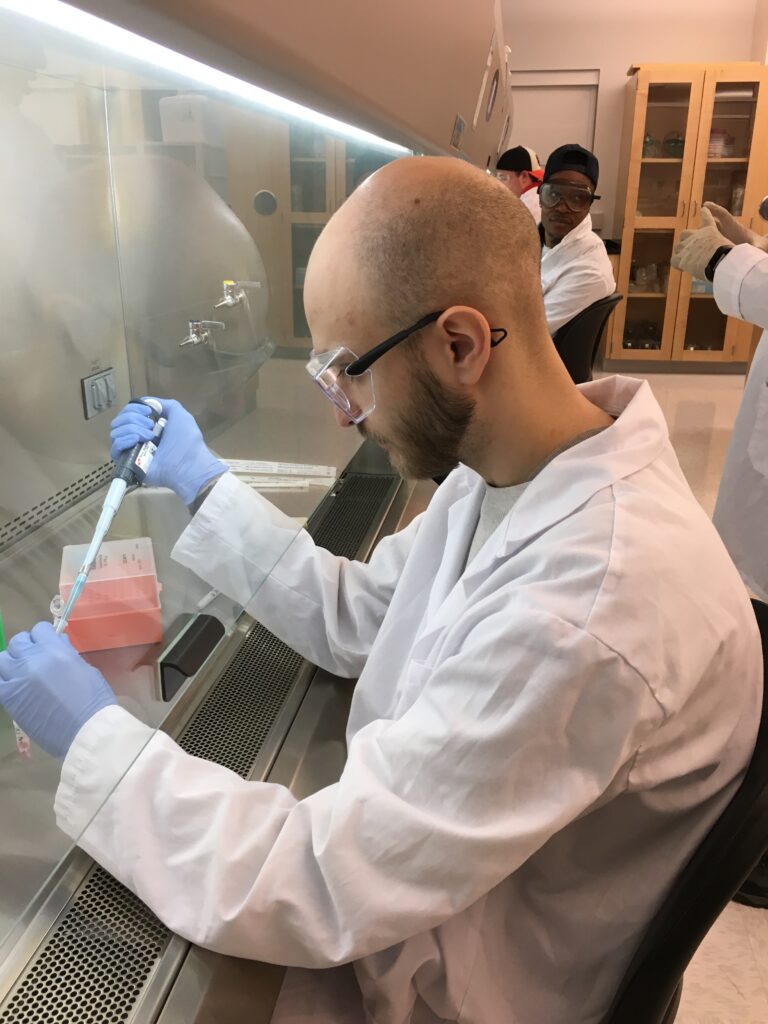 A man in lab gear works on research