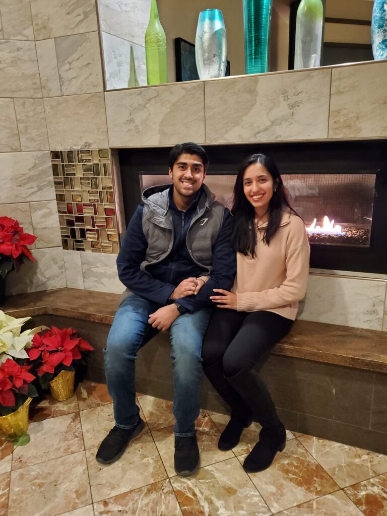 A couple poses in front of a fireplace