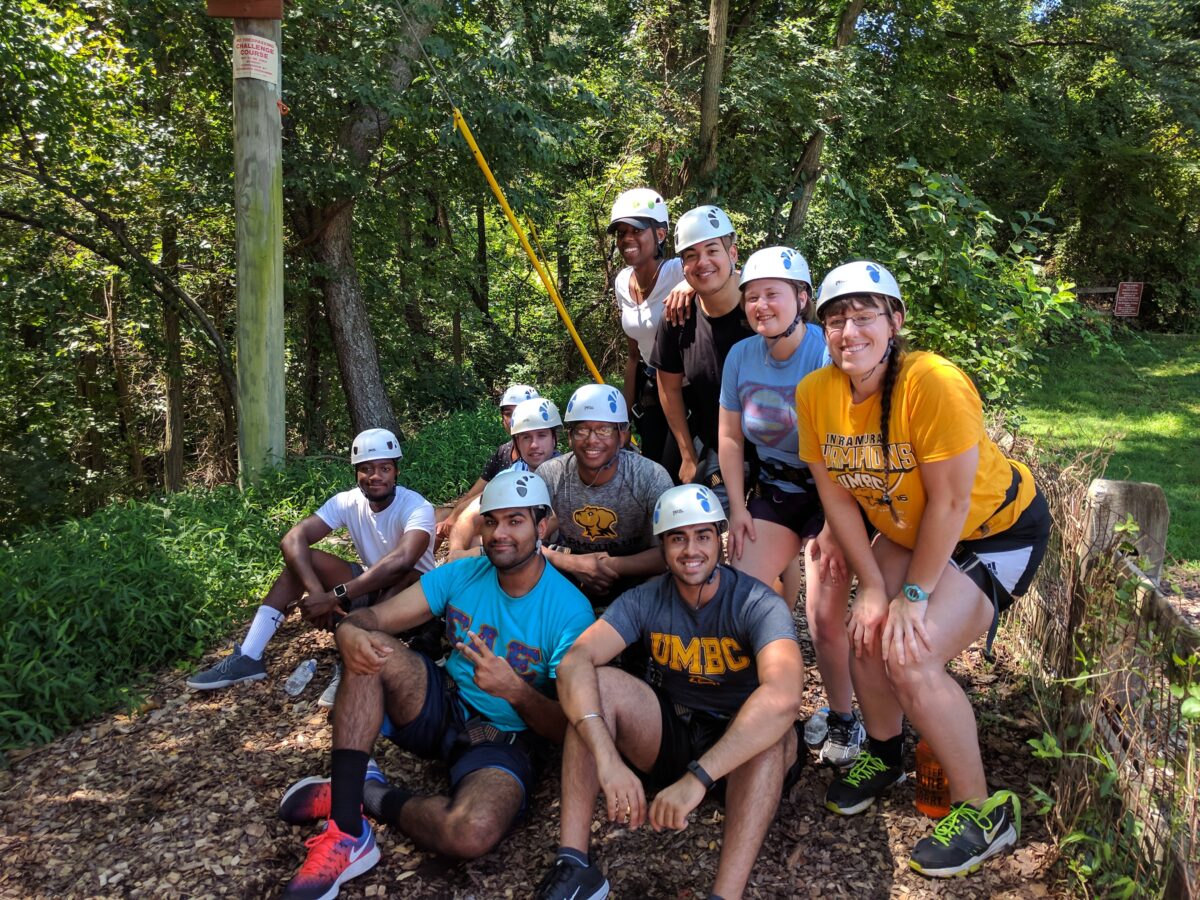 Students in climbing helmets pose in the woods