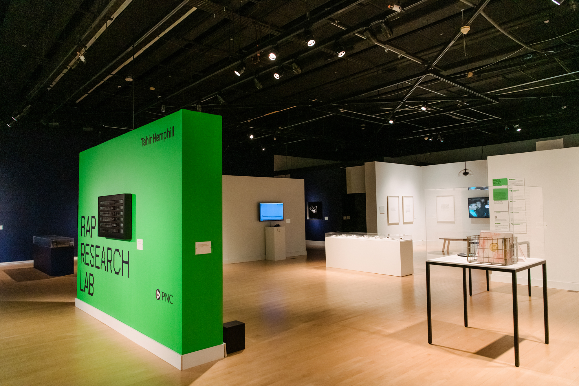 A view of an art gallery shows a green panel with words Rap Research Lab