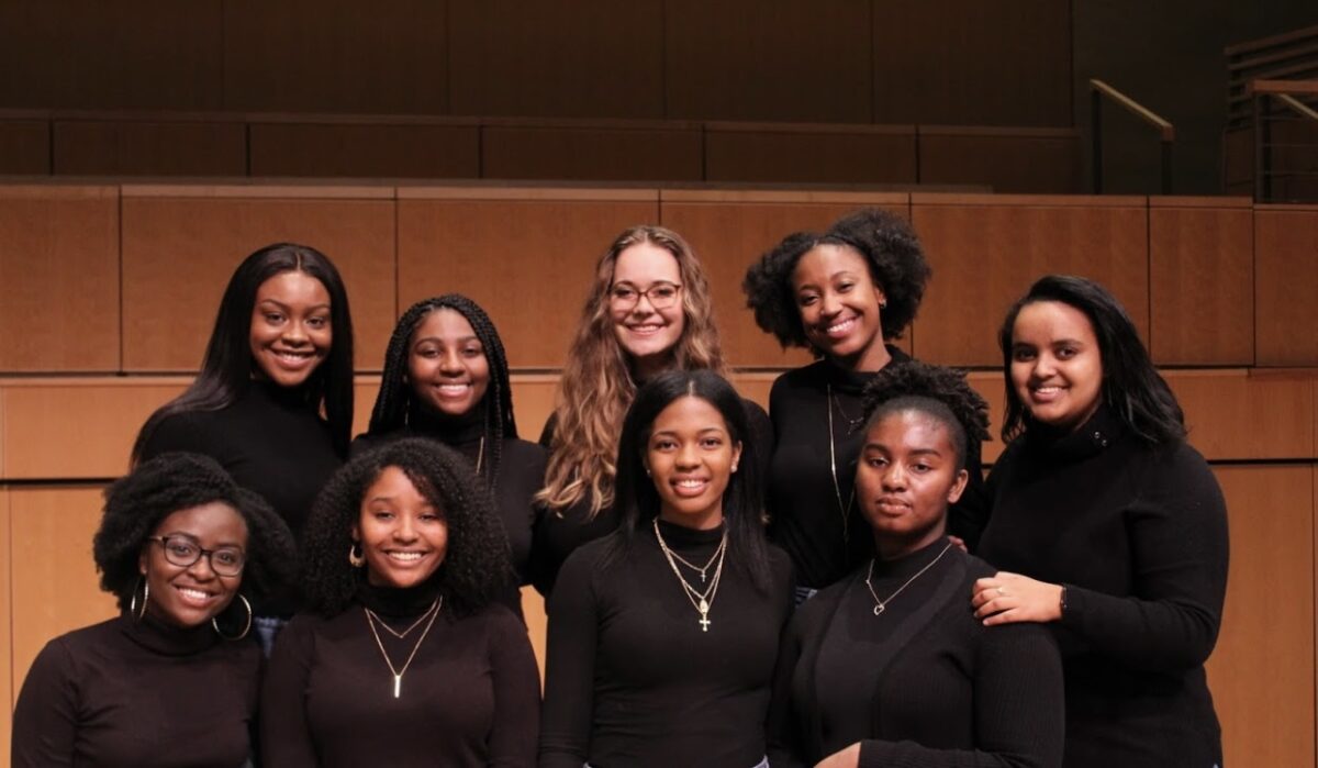 group of nine students all dressed in black on the UMBC concert hall stage