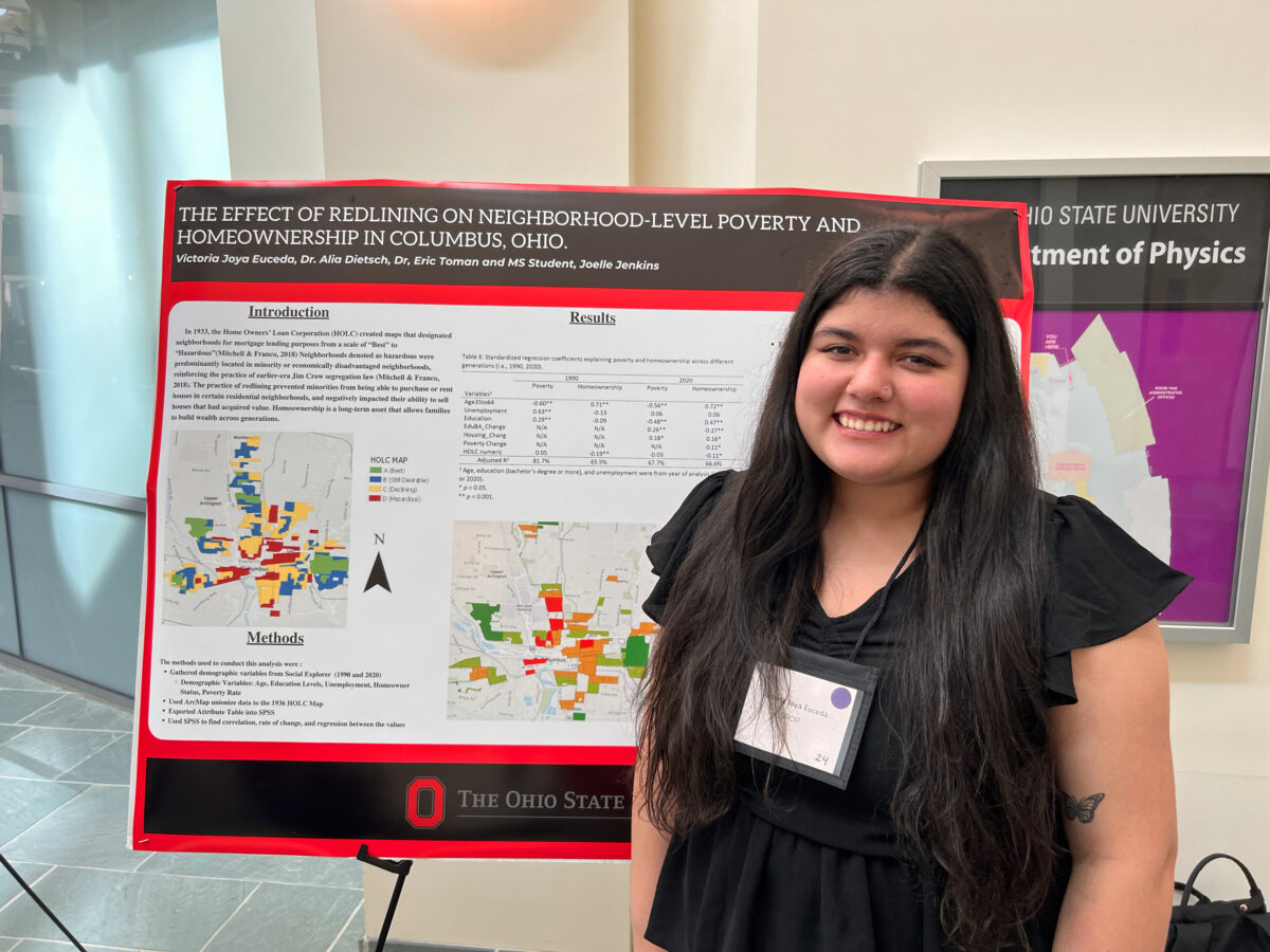 A first-gen McNair Scholar stands in front of their research poster of redlining neighborhoods