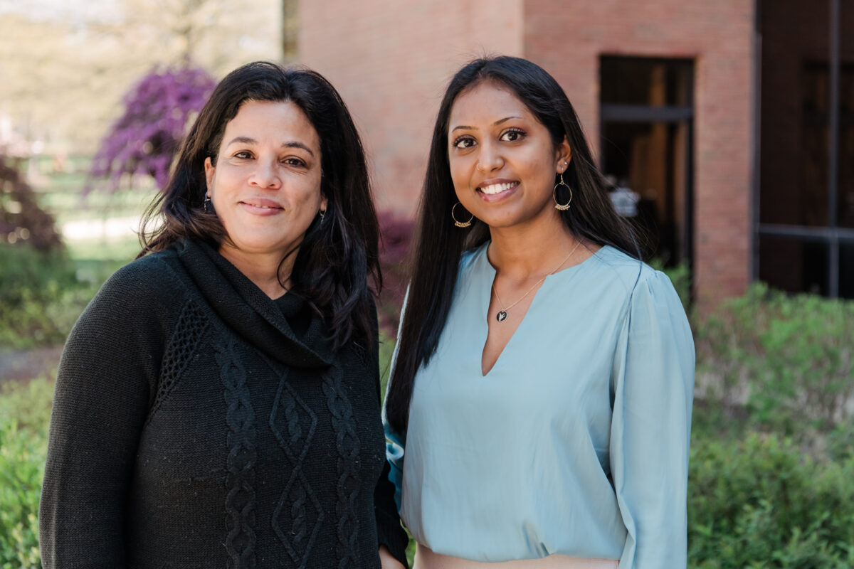 student and faculty member smiling at camera, outdoors