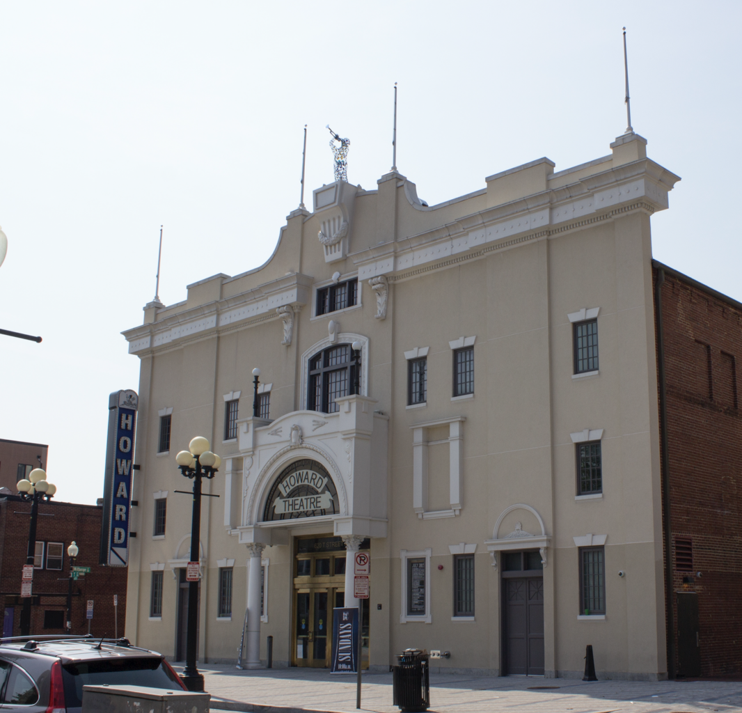 A three story tan and white theatre where Black Vaudeville was performed with the words Howard on the marquee.