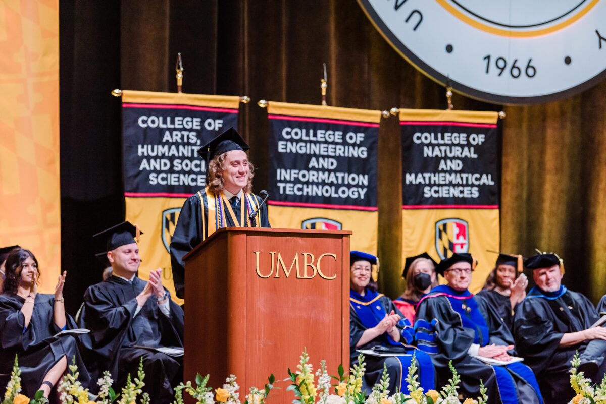 Class of 2023 valedictorian for the College of Arts, Humanities, and Social Sciences; School of Social Work; and Erickson School of Aging Studies morning ceremony, Zinedine Partipilo Cornielles, speaks on the graduation stage. 