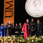 Sheares Ashby stands with University System of Maryland Chancellor Jay Perman and Board of Regents Chair Linda Gooden in front of the UMBC seal at her investiture ceremony.