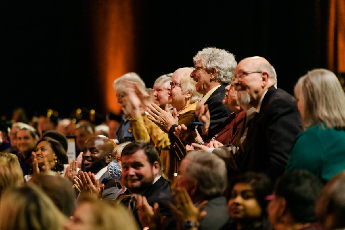 A row stands up in the audience to applause