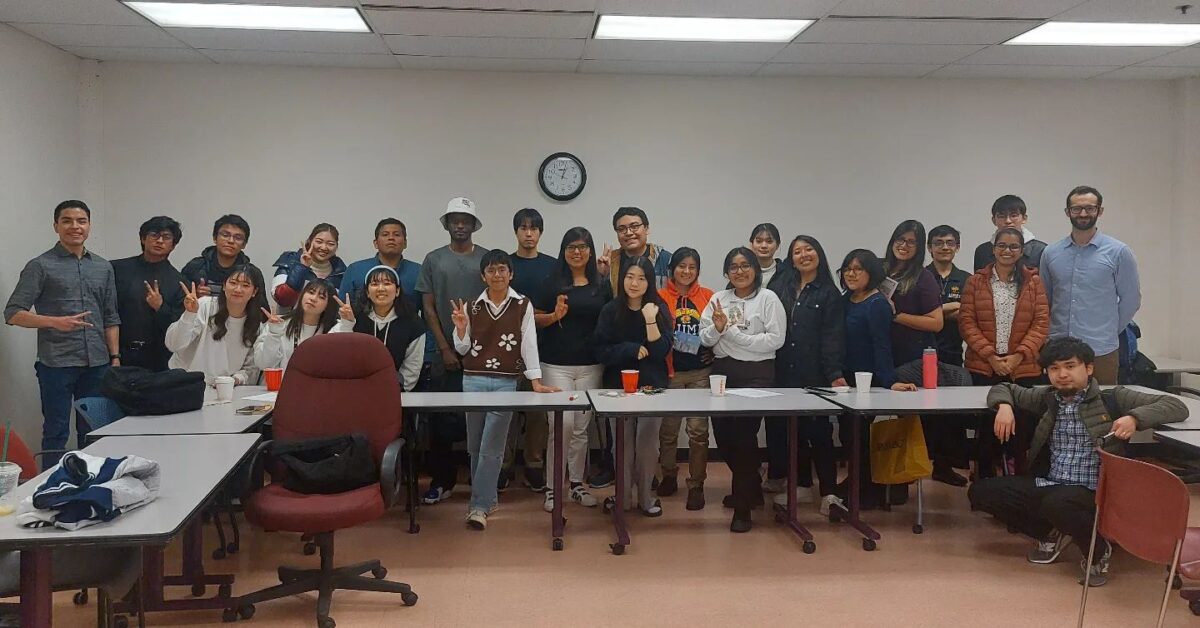 A group of international students with their langauge instructor, some posing with the peace finger signs.