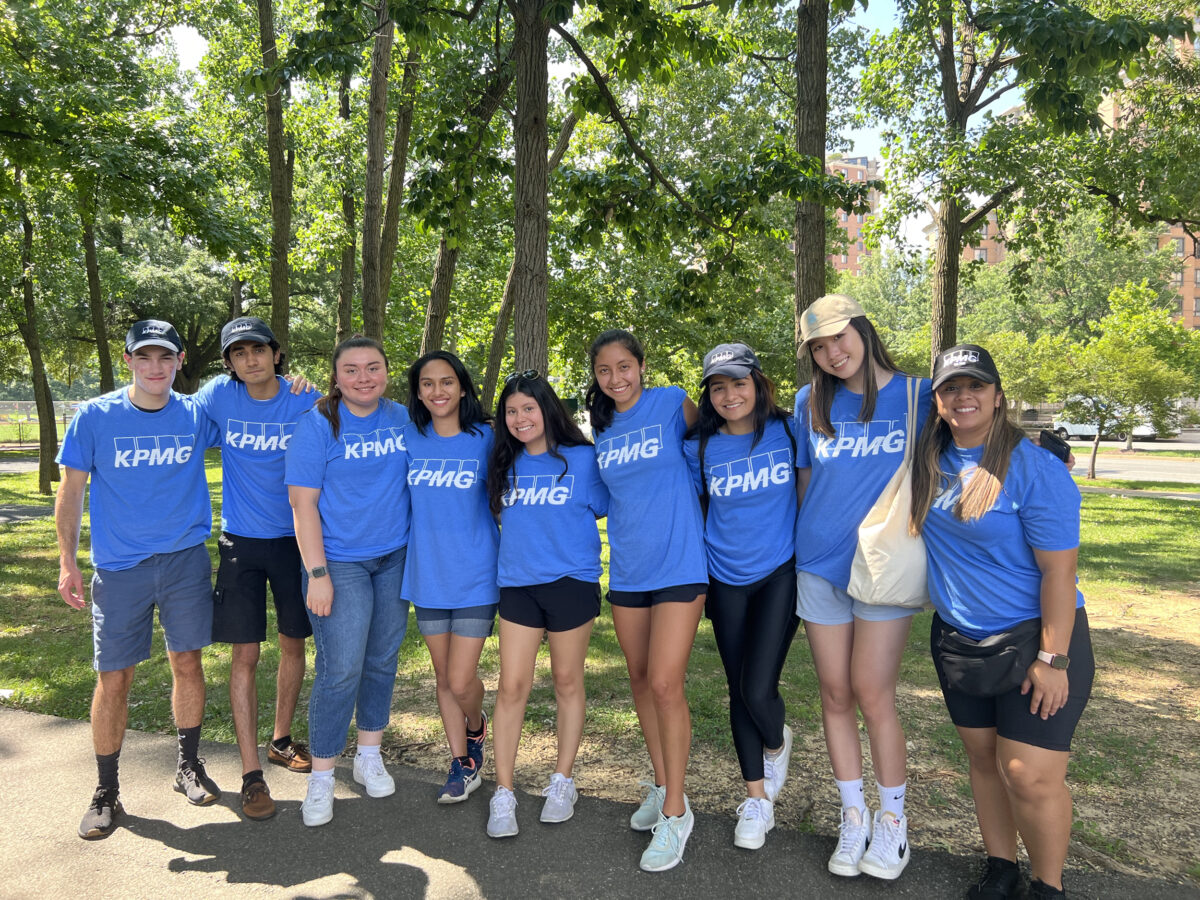 A group of nine people wear blue shirts that say KPMG