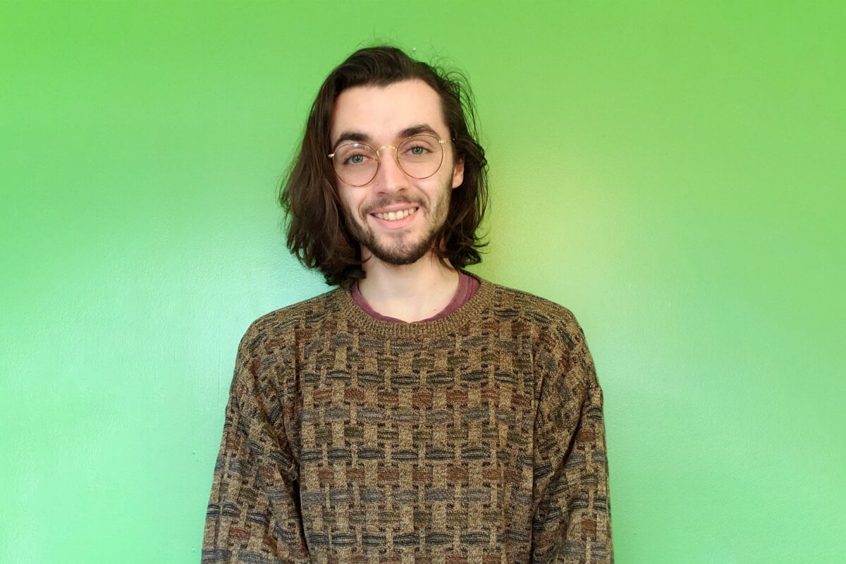 Man smiles at camera against a green background.