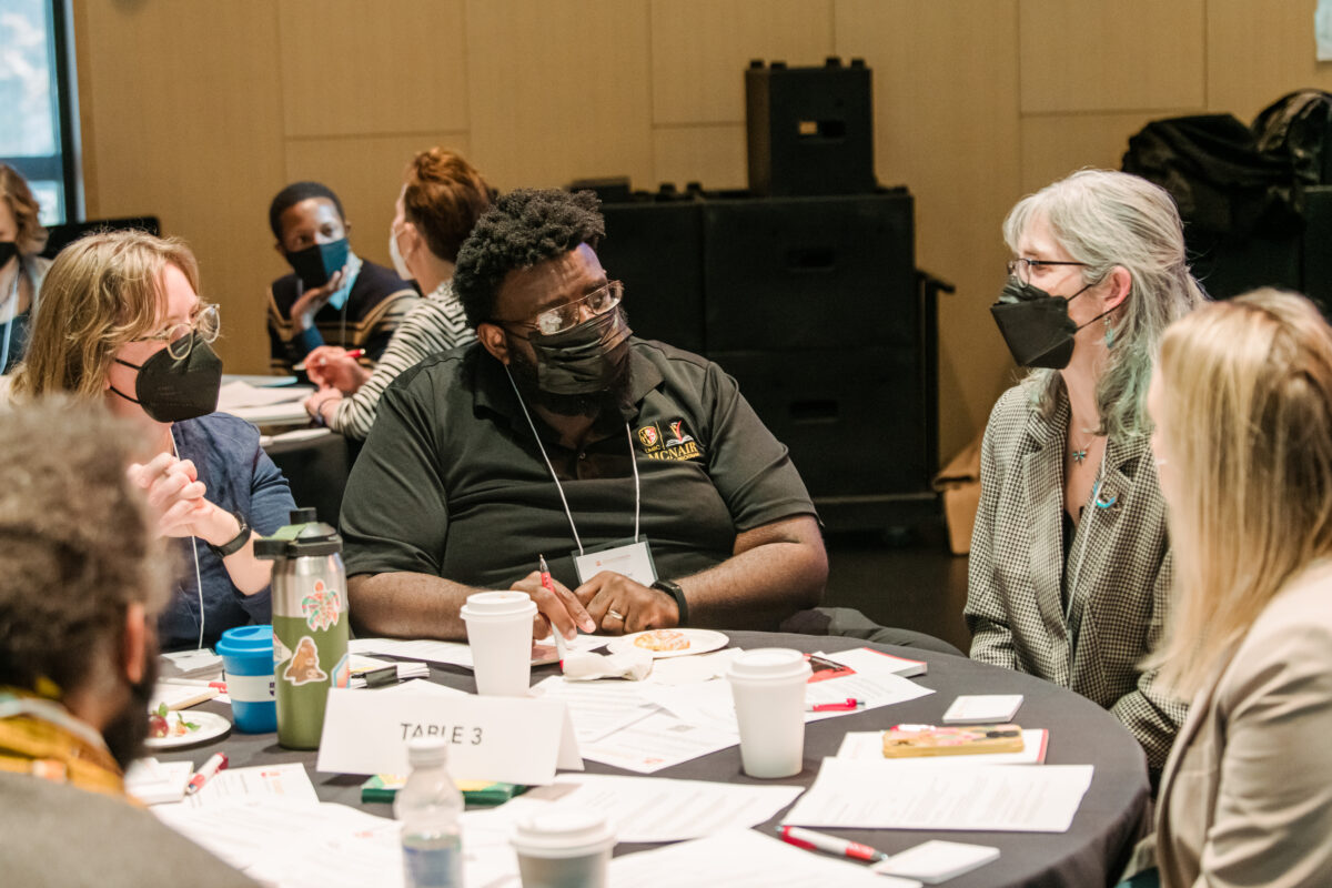 A group of researchers gather at a table to discuss work