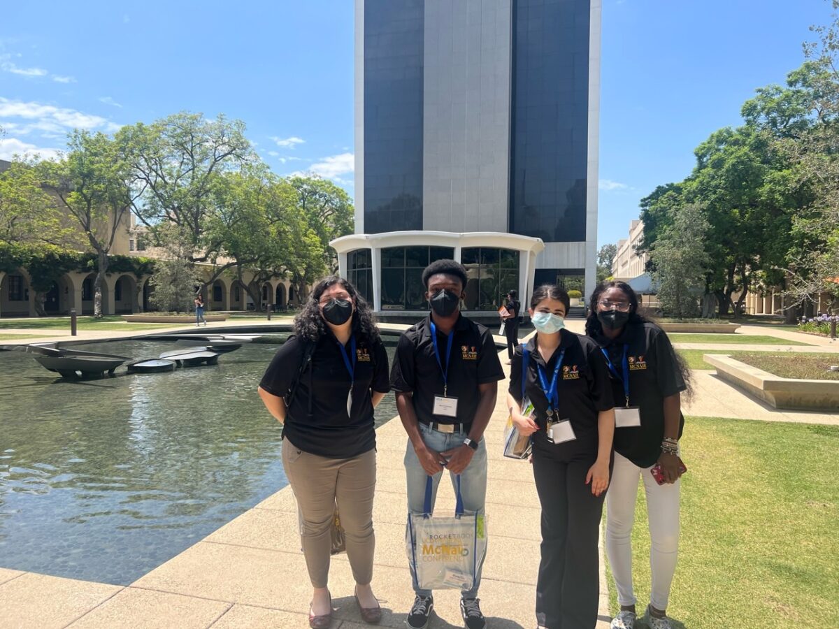 Four McNair Scholar students wearing masking, posing in front of a building.  