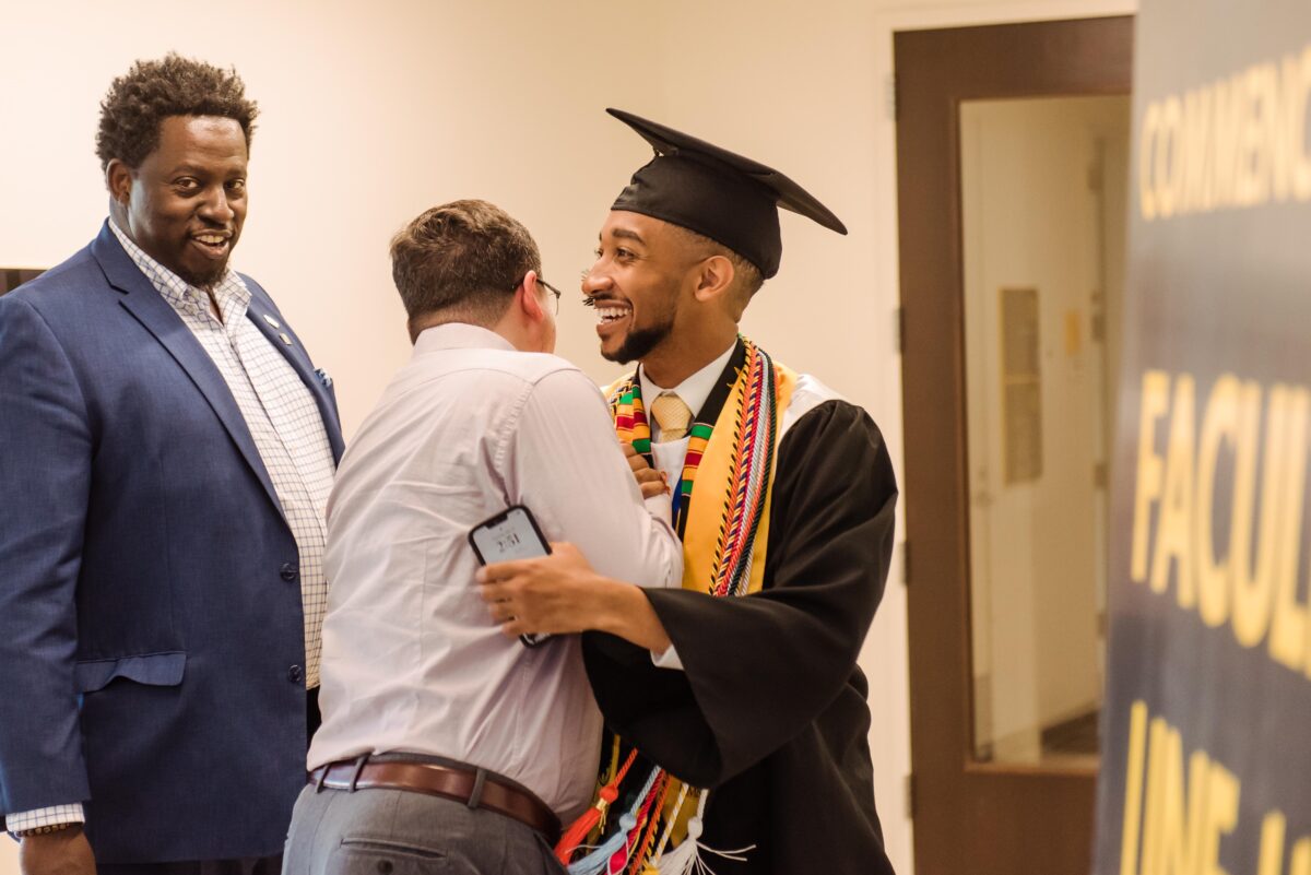 A graduating student is hugged and congratulated.