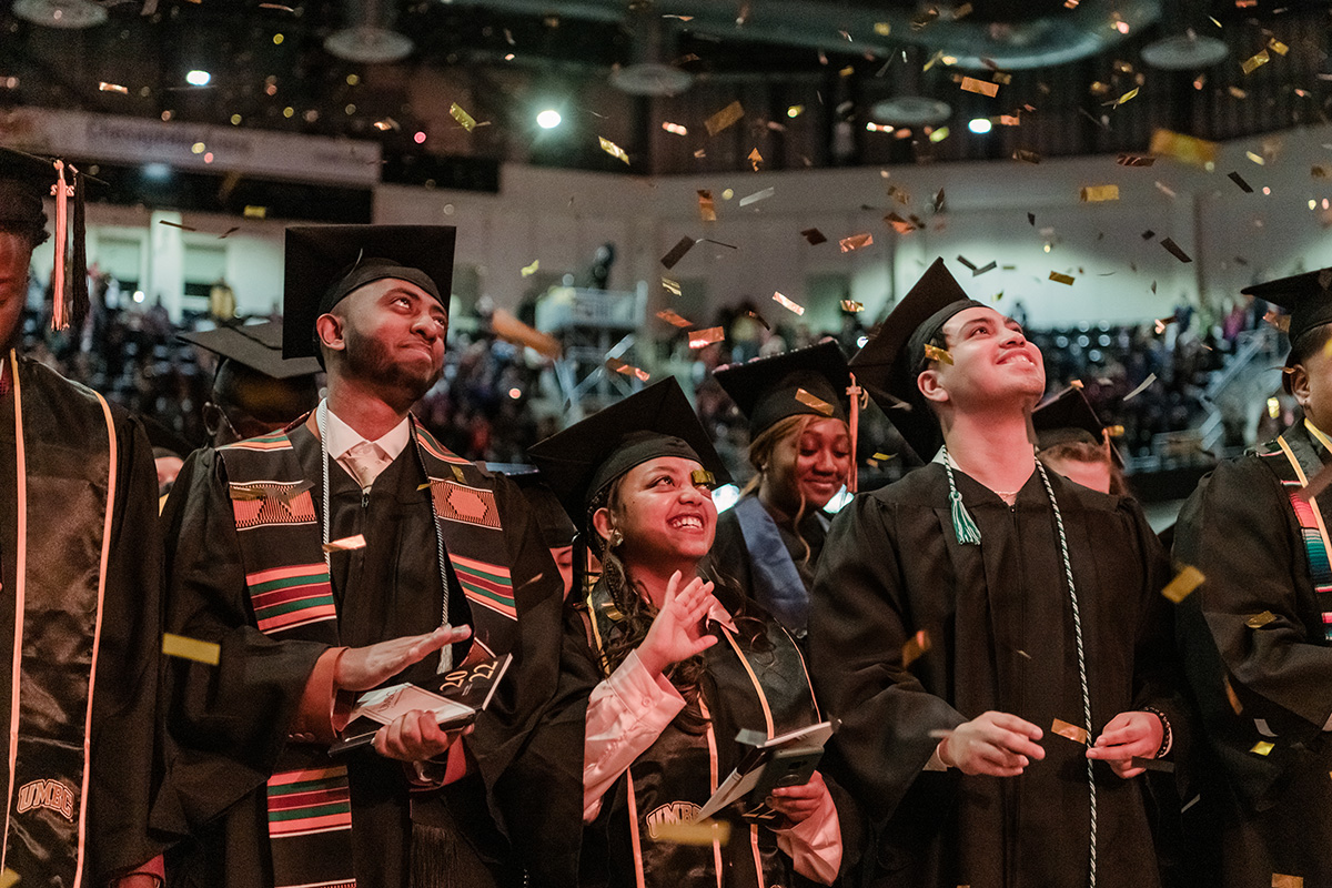 Happy UMBC graduates celebrating together with confetti filling up the room.