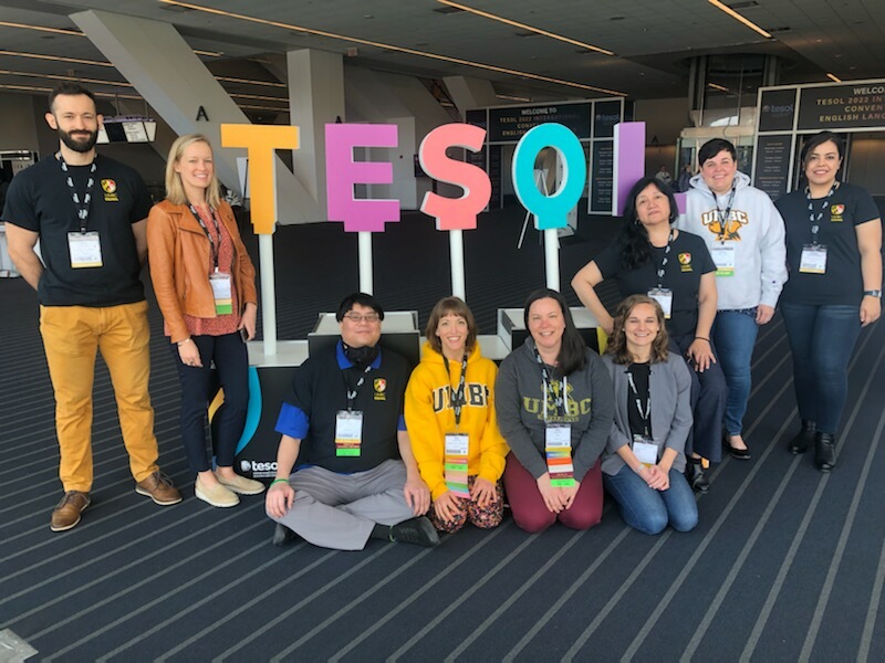 None people wearing UMBC clothing, some sitting and some standing, at the TESOL International Convention in 2022, focused on teaching the English language. 