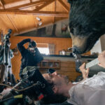 in a behind the scenes shot on a film set, a man fends off a pretend bear with a door