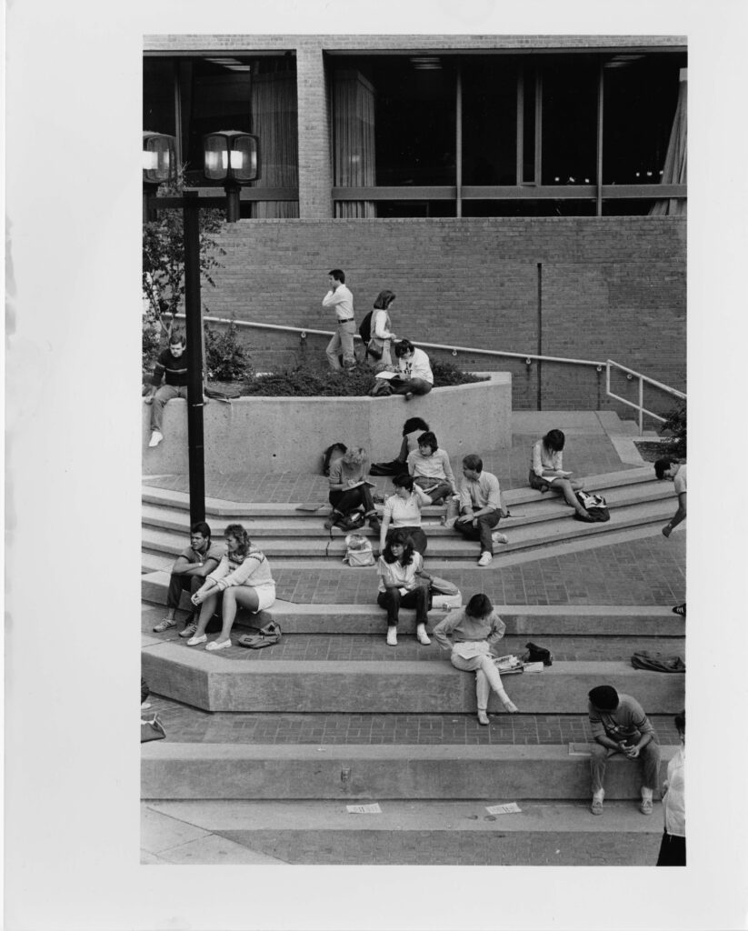 A group of students sit on outdoor concrete steps.