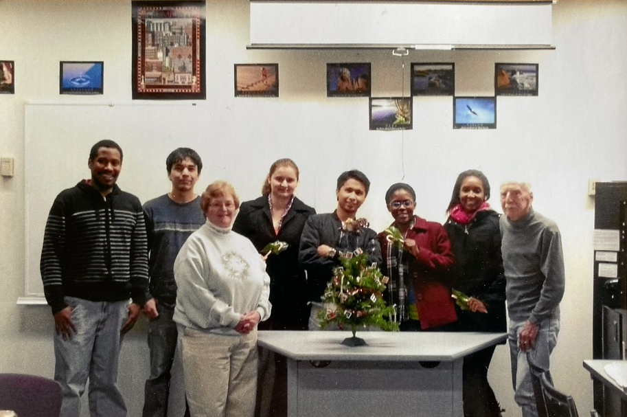 a group of staff and students stand in front of a wall with pictures of international destinations