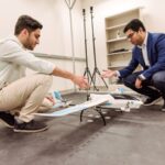 Two people look at model plane in lab space.