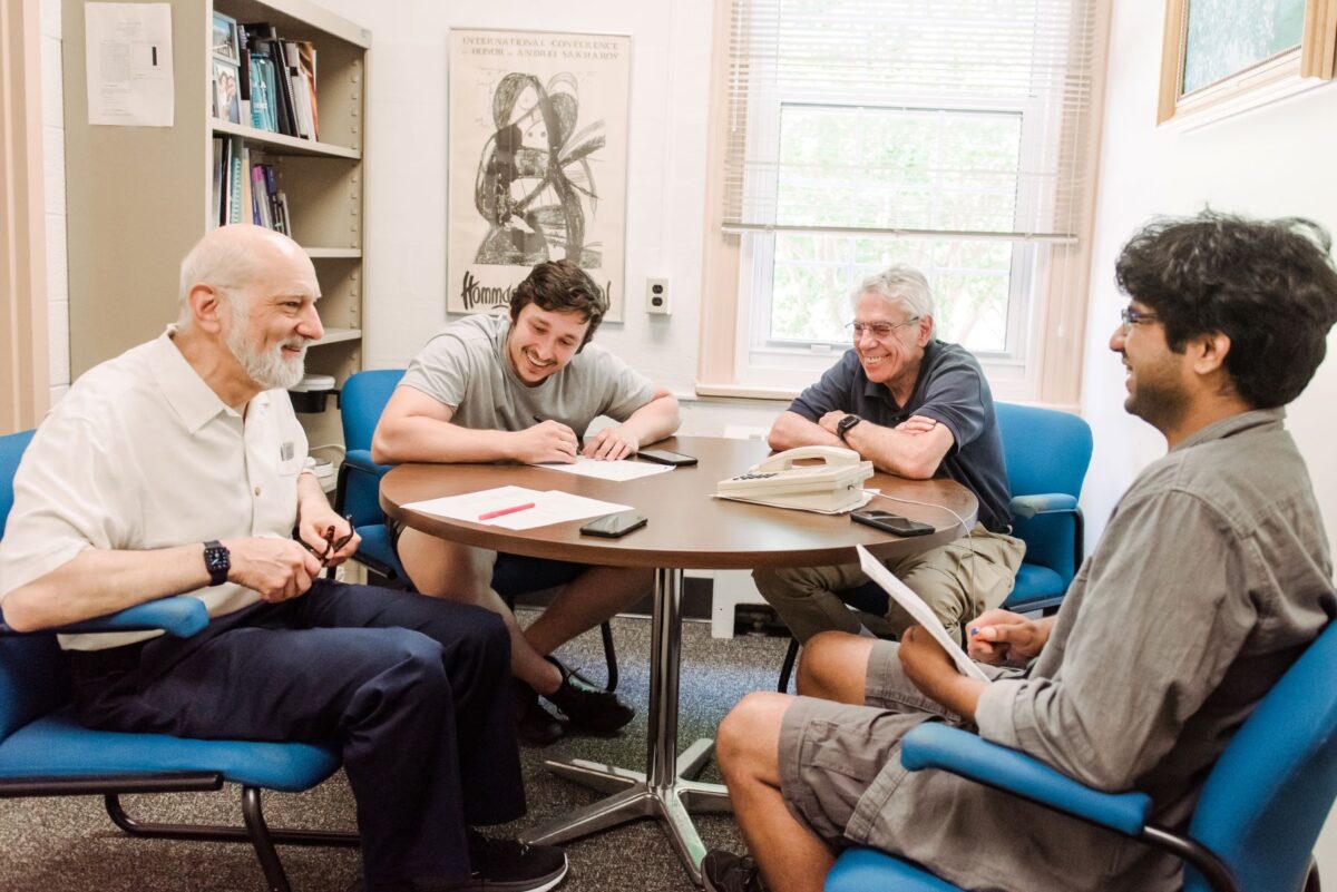 Four people sit around table in conversation.