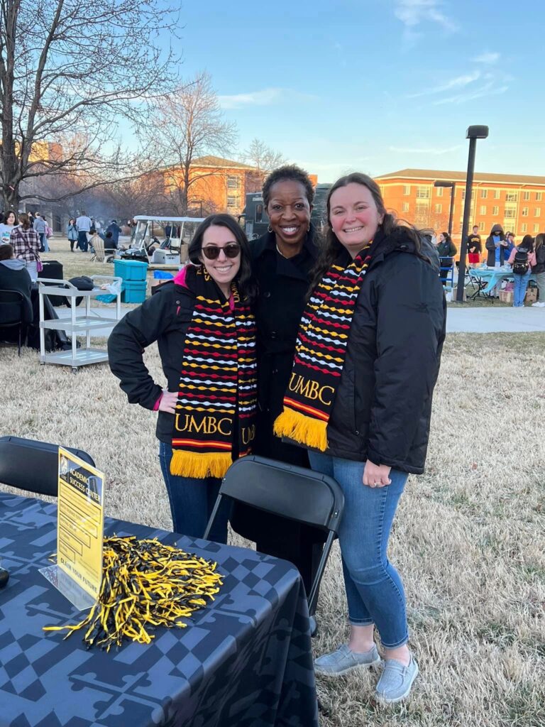 Three women stand shoulder to shoulder on a winter day.