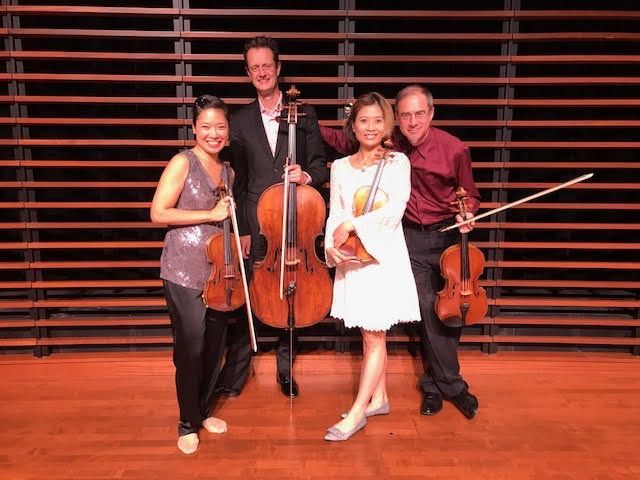 Four musicians pose with their instruments