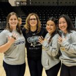 Jamie Gurganus, second from left, poses with softball players displaying their 2022 America East Championship jewelry.
