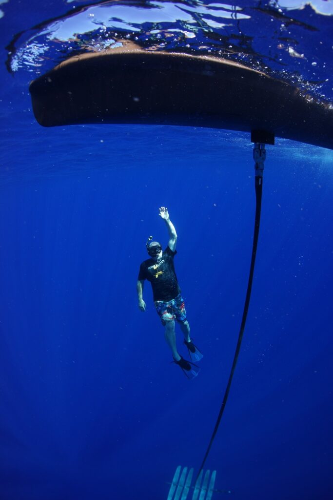 A man underwater with scuba gear inspects a piece of equipment