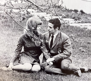 black and white photo of a man and a woman cuddling under a tree