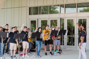 pep band director Corbett-Wilson leads the band outside of the Event Center