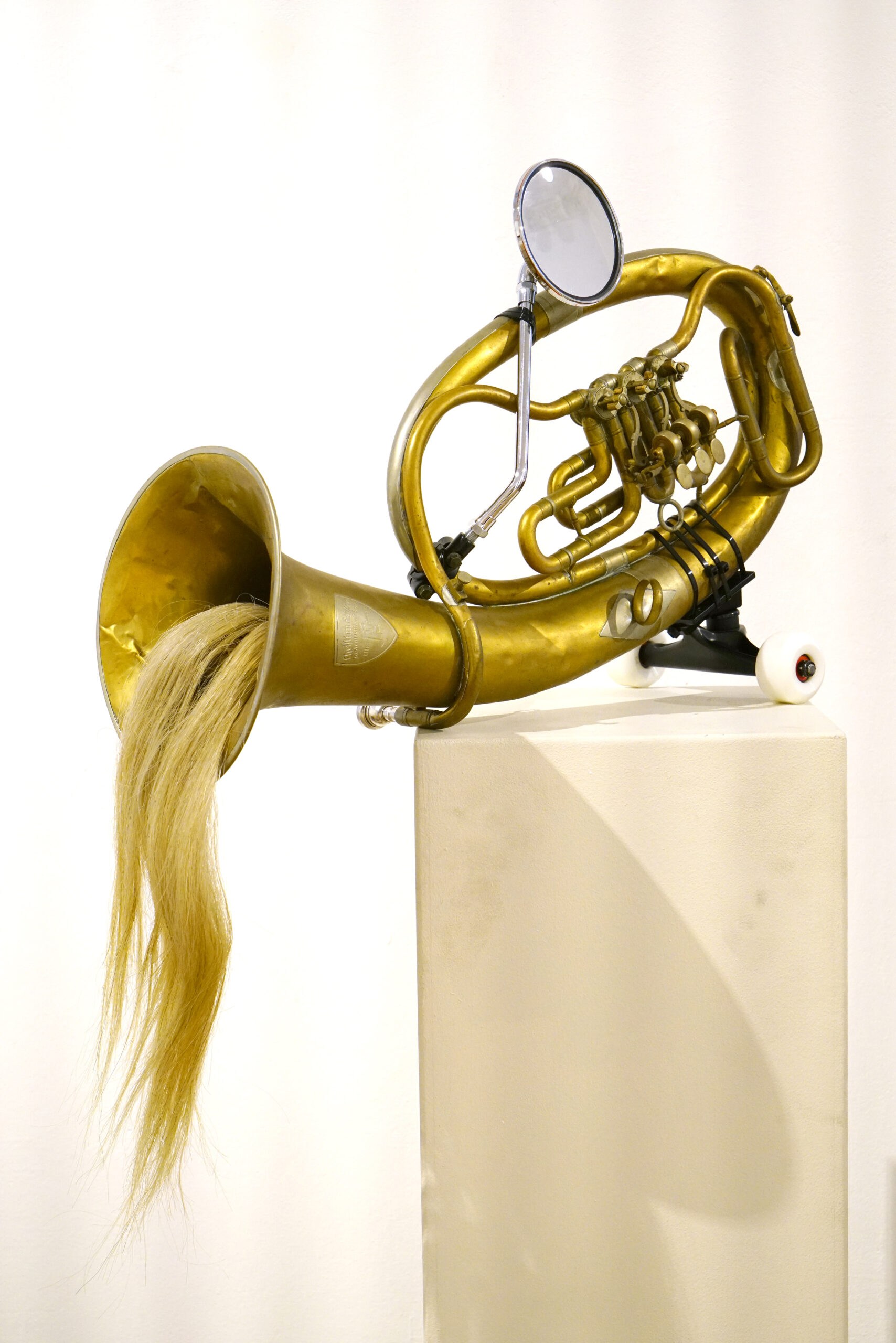 A surreal-looking piece of artwork includes a brass instrument with hair coming out of its bell